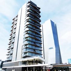 a very tall building with many windows next to some cars and people on the street