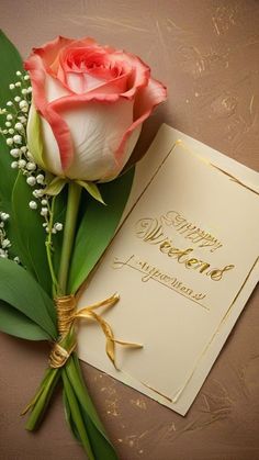 a pink rose sitting on top of a table next to a card and some baby's breath