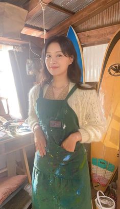 a woman in an apron standing next to a surfboard