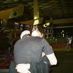 some people are walking around in an airport terminal at night with their backs turned to the camera