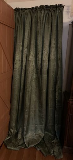 a green curtain hanging on the side of a wooden door