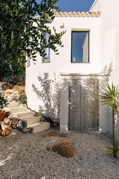 a white house with a wooden door and steps leading up to the front yard area