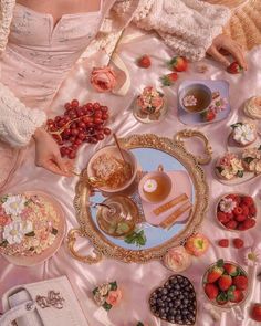 a woman sitting at a table filled with food and desserts next to other dishes