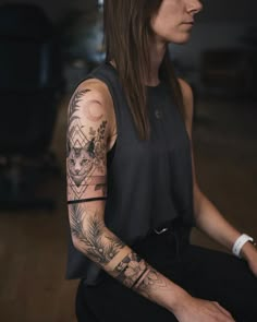 a woman with long hair and tattoos on her arm is sitting in a dark room