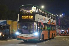 a double decker bus is driving down the street at night with other vehicles behind it