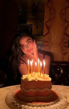 a woman sitting in front of a cake with lit candles