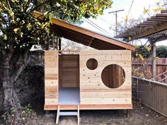 a small wooden outhouse sitting in the middle of a yard next to a tree