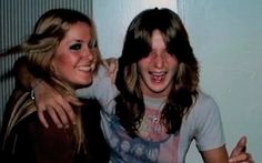 two young women standing next to each other with their arms around one another and smiling at the camera