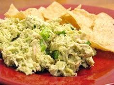 a red plate topped with guacamole and tortilla chips