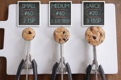 three cookie doughnuts are being held by tongs on a white board with small signs