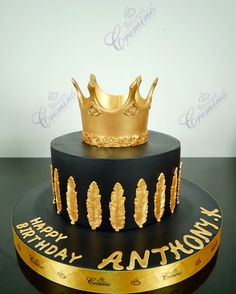 a black and gold birthday cake with a crown on top that says happy birthday anthony