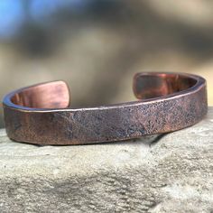 A handmade solid copper cuff bracelet with a rugged concrete finish for your rugged masculine man.  The classic heavyweight cuff that no man should be without. This bracelet is as unique as he is, no two will ever be alike.  How to determine your size:  Using the directions in the photos, choose the most appropriate size.  6 inch is the average size for women, and 7 inch for men.  If you aren't sure of the right size, it's always better to go too big instead of too small as I can size bracelets down if needed. Caring for your copper jewelry:   Tarnish and discoloration is a normal part of copper jewelry and is to be expected.  Periodically you should wash your copper jewelry in warm soapy water, making sure to dry it thoroughly with a soft cloth. In between washing, buff it with a polishin Copper Bracelets, Mens Copper Bracelet Western, Men Copper Bracelet Handmade, Mens Silver And Copper Cuff Bracelets, Unique Copper Cuff Bracelet With Patina, Mens Copper Bracelet, Mens Rugged, Artisan Silver-colored Copper Cuff Bracelet, Concrete Finish