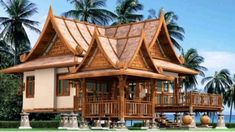 a large wooden house sitting on top of a lush green field next to palm trees