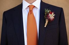 a man wearing an orange tie and a boutonniere