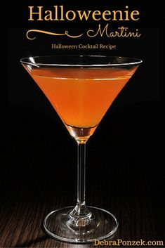 a halloween martini in a coupe glass on a table with the words, halloween martini written above it