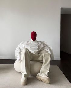 a person sitting in a chair with a red hat on their head and hands behind his back