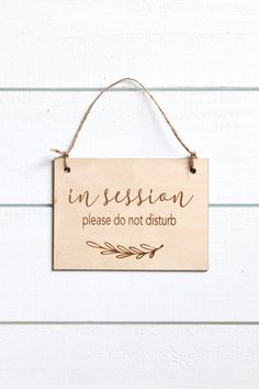 a wooden sign hanging on the side of a building that says, in session please don't disturb