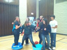 a group of young people standing around each other in a gym with one woman covering her eyes