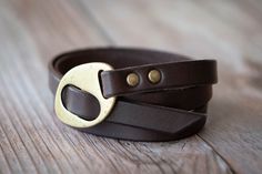 a brown leather belt with a brass buckle on it sitting on a wooden table next to a pair of scissors