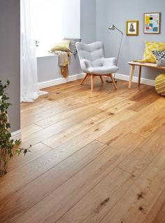 a living room with hard wood floors and white furniture, including a gray chair in the corner