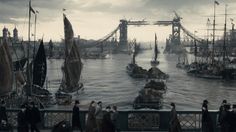 many people are walking near the water and boats in the harbor with tall cranes behind them