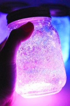 a hand is holding a jar filled with glowing liquid in the dark, and it's glows brightly