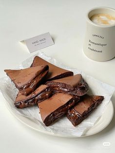 there are many pieces of chocolate cake on the plate next to a cup of coffee