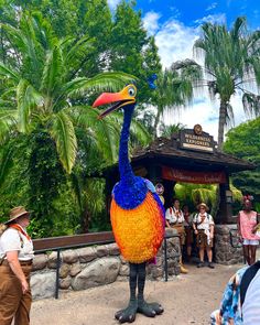 a man standing next to a colorful bird statue