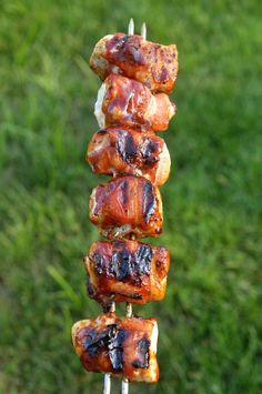 several skewers of meat sitting on top of each other in front of green grass