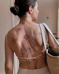 a woman with tattoos on her back holding a basket