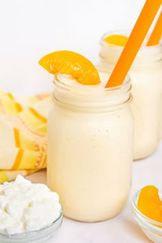 two mason jars filled with orange slices and whipped cream, next to an orange slice