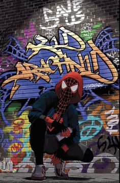 a spider man squatting in front of a graffiti covered wall with his hands on his knees