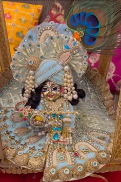 a statue of a woman dressed in blue and white with feathers on her head, surrounded by other decorative items