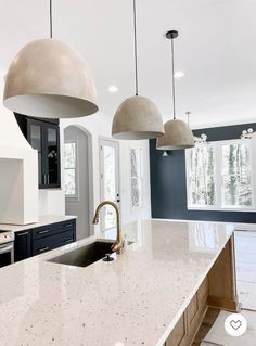 a kitchen with two pendant lights hanging over the sink and an island in front of it