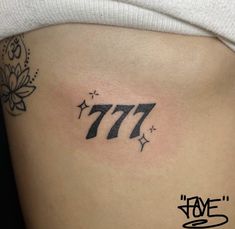 a woman's stomach with the number 777 tattoo on her left side ribcage