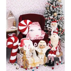 a group of santa clause figurines sitting next to a christmas tree with candy canes