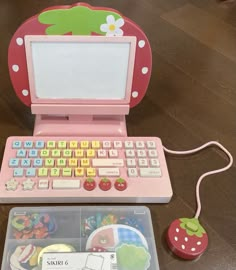 a pink laptop computer sitting on top of a wooden table next to a plastic mouse