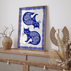 a blue and white painting sitting on top of a wooden shelf next to vases