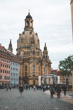 people are walking around in front of a large building with a dome on the top