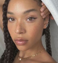 a close up of a woman with freckles on her head and braids in her hair