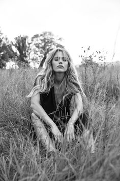 a woman is sitting in the tall grass