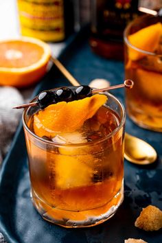 an old fashioned cocktail with orange slices and black olives