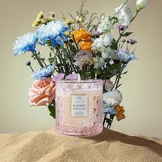 a vase filled with flowers sitting on top of sand