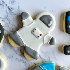 cookies decorated to look like an astronaut's suit on a marble counter top with chalk markers