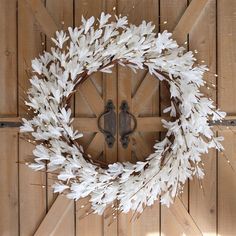 a wreath with white flowers is hanging on a wooden paneled wall in front of a door