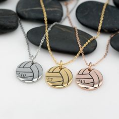 three volleyball necklaces sitting on top of some rocks