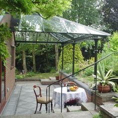 a patio with a table and chairs under a glass roof