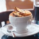 a white cup filled with cookies sitting on top of a table next to a plate