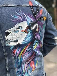 the back of a person wearing a jean jacket with a lion painted on it's chest