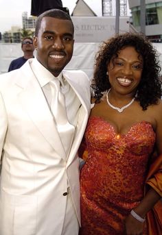 a man and woman standing next to each other in front of a white wall with people